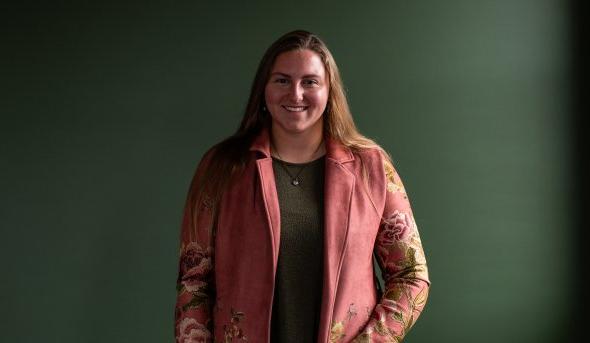 Photo of a woman standing against a dark background.